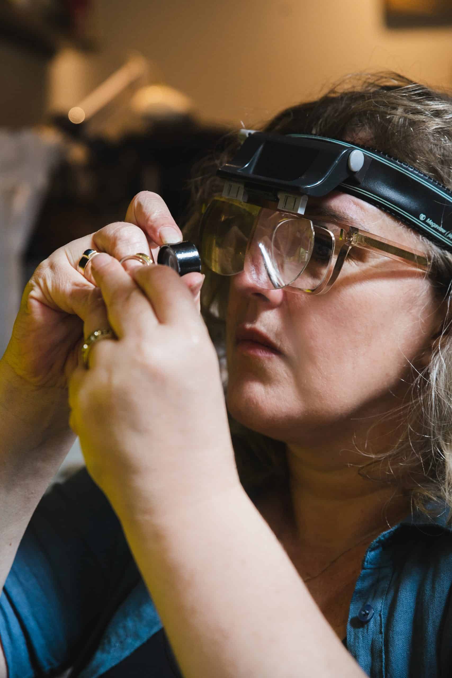 Margriet van Burgant die een edelsteen inspecteert