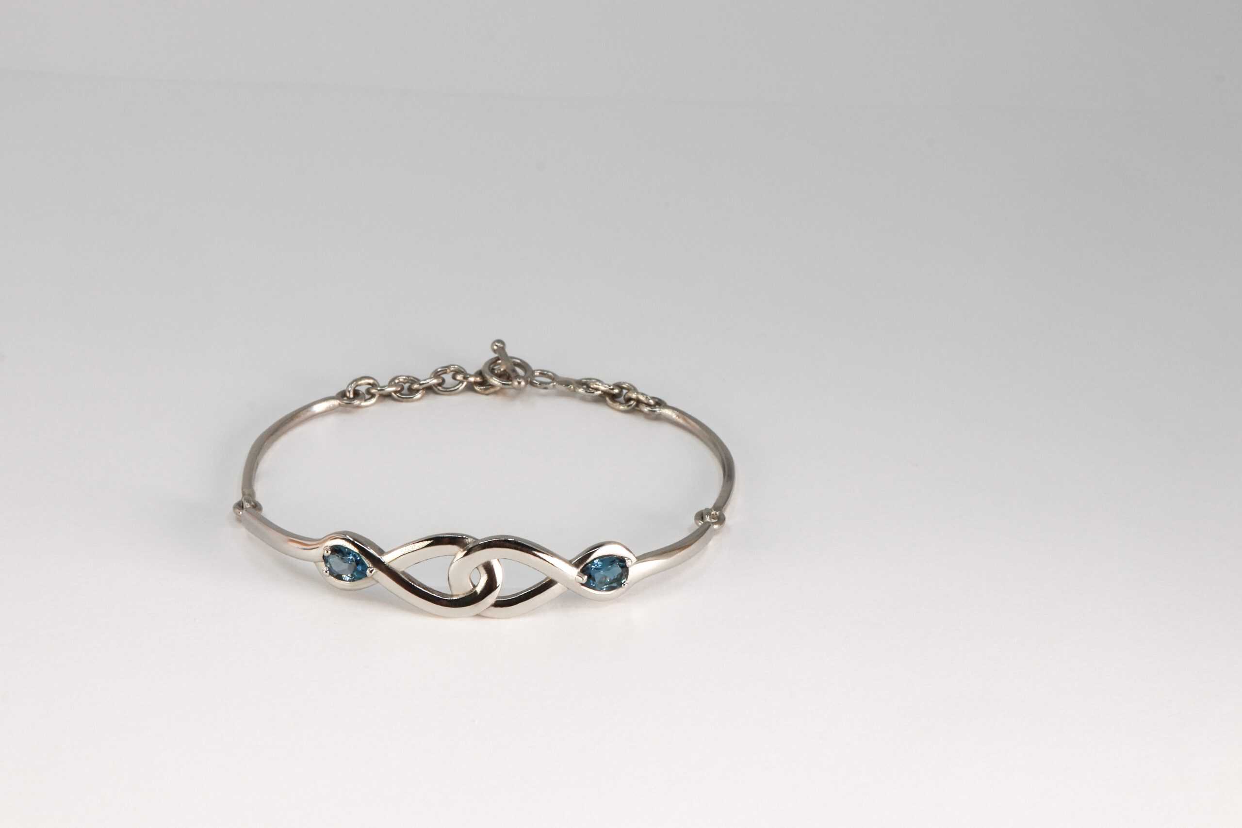 Armband met infinity teken van platina met London blue topaas door Burgant gemaakt.