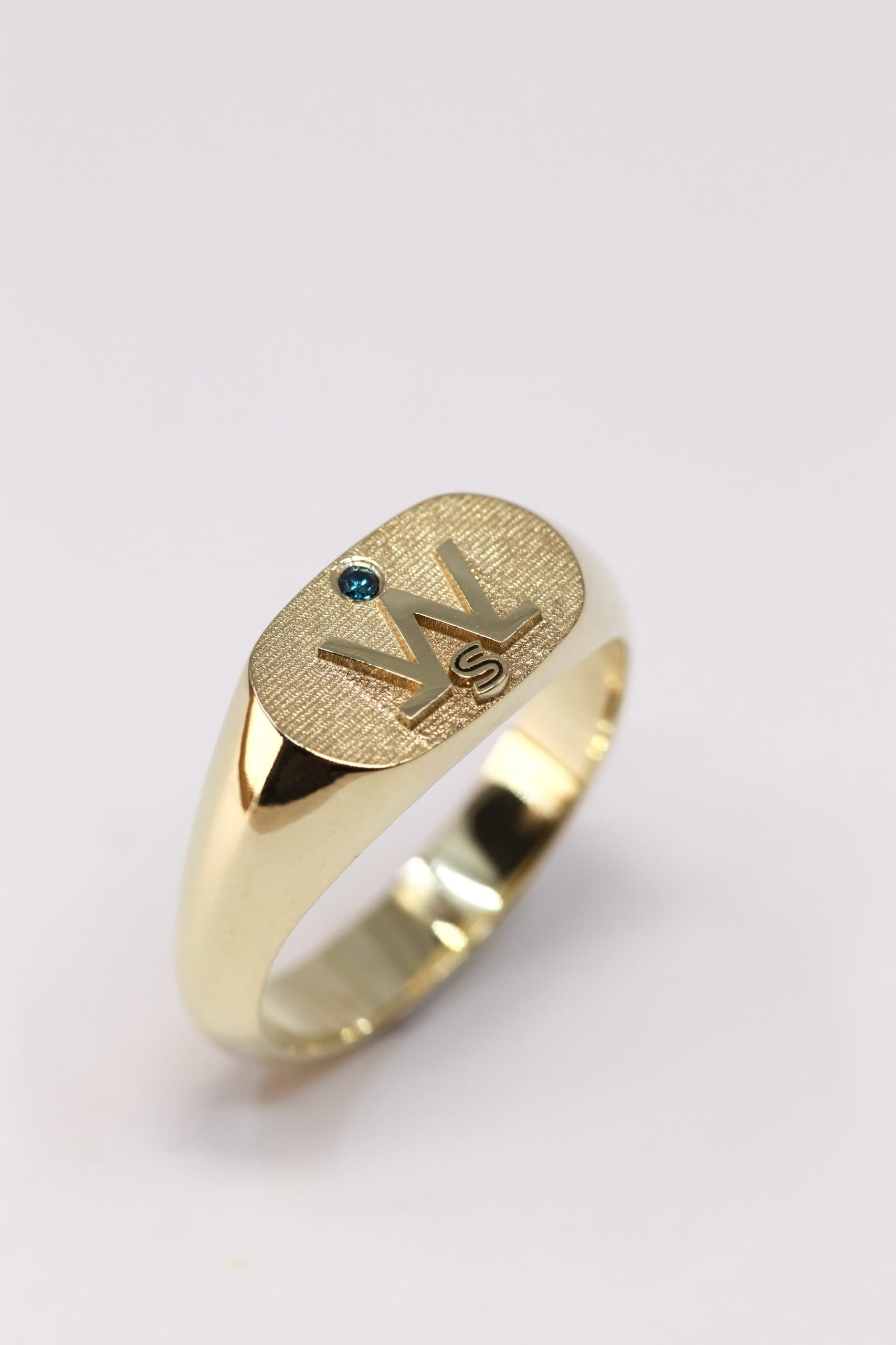 Een bijzondere herenring met monogram en blauwe diamant, vervaardigd door Burgant.