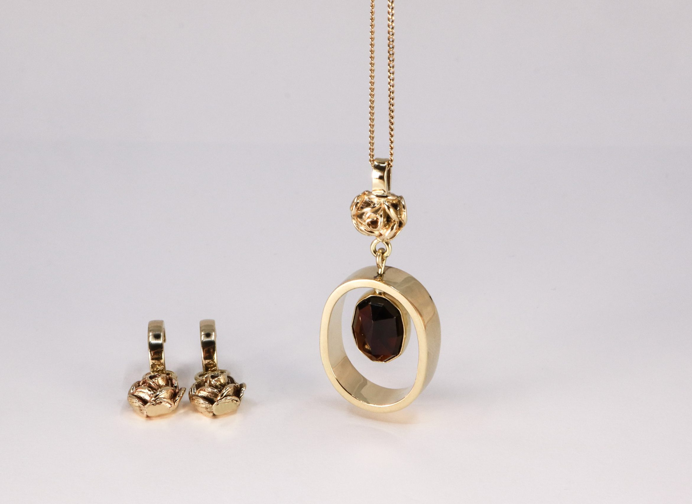 De gouden set ROSE met een ketting, roos en granaat en twee bijpassende oorhangers, vervaardigd door Burgant.