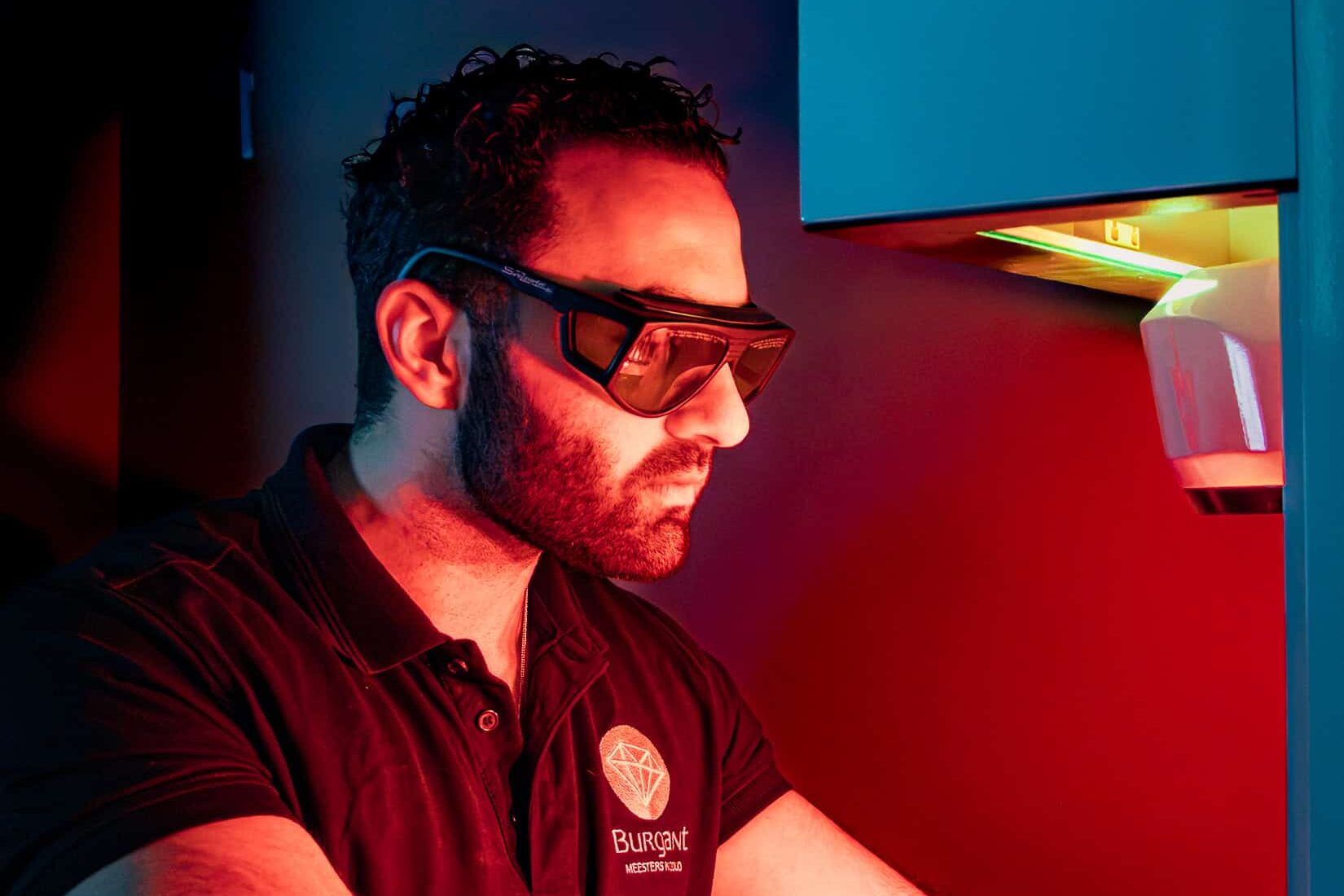 Bram Burger werkzaam achter de lasermachine in het atelier van Burgant tijdens het graveren van een maatwerk sieraad.