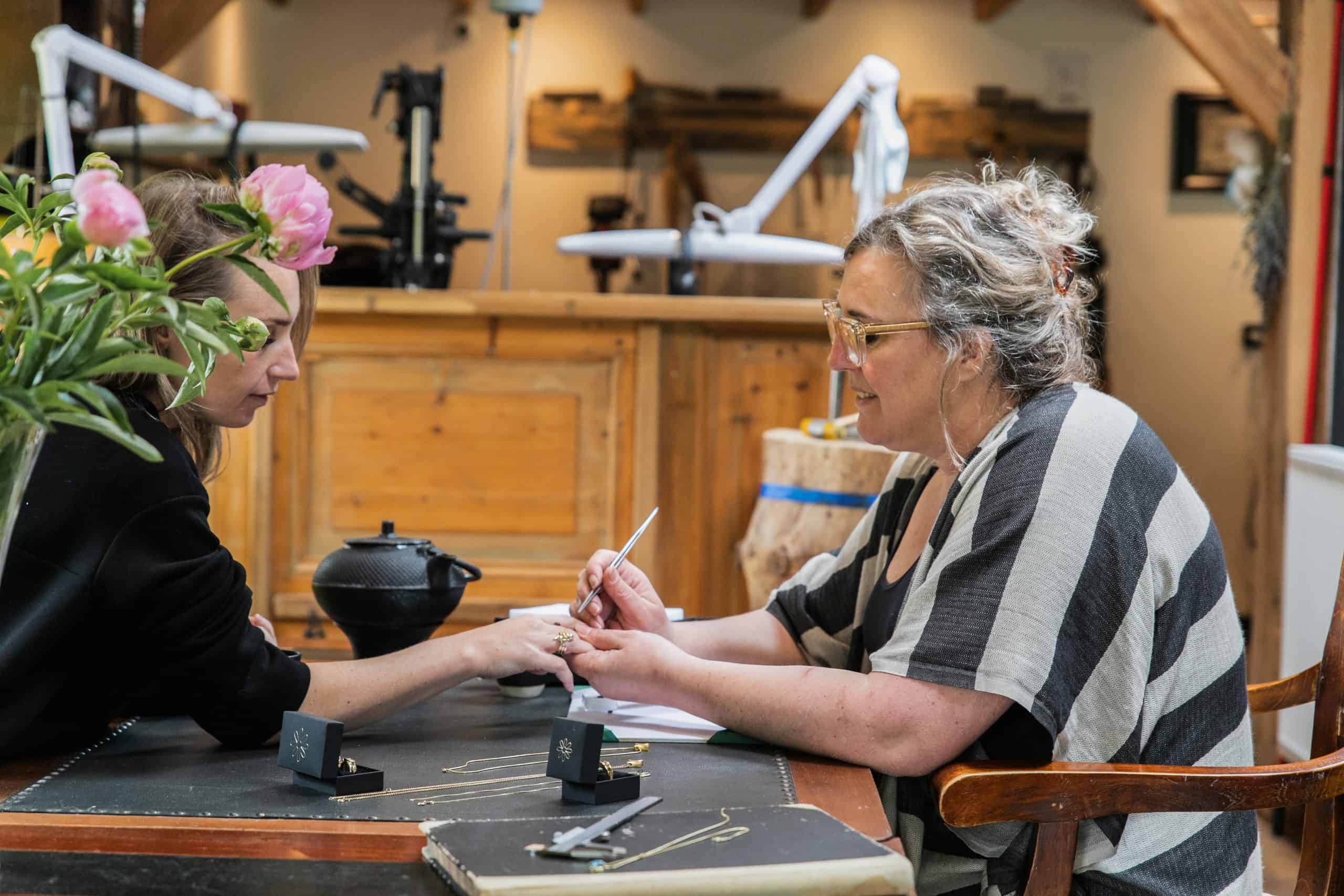 Goudsmid Margriet past sieraden bij een klant in het atelier van Burgant tijdens een persoonlijk ontwerpgesprek.
