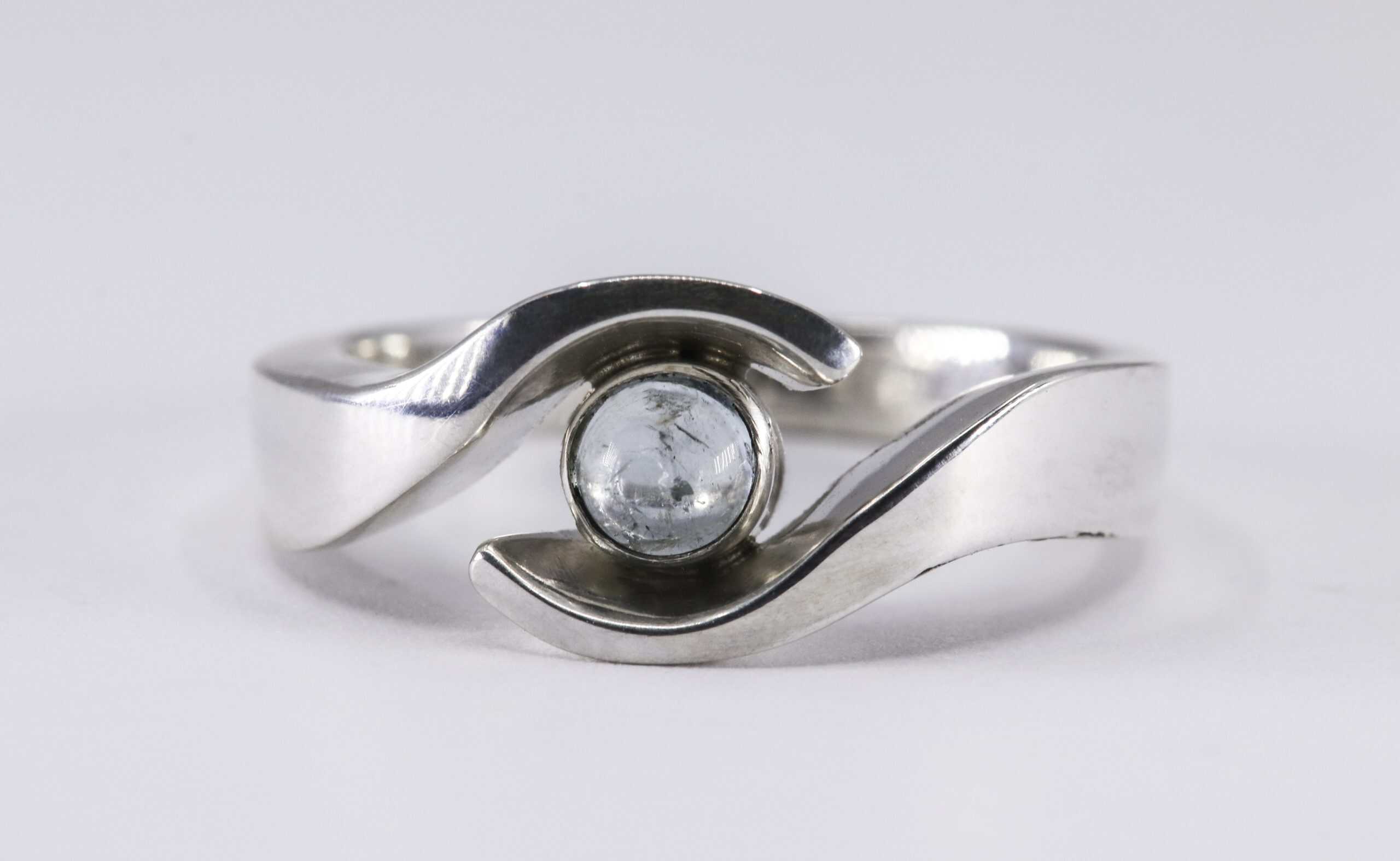 Ring OMARMING met aquamarijn en moedermelkverwerking, vervaardigd door Burgant als persoonlijk herinneringssieraad.