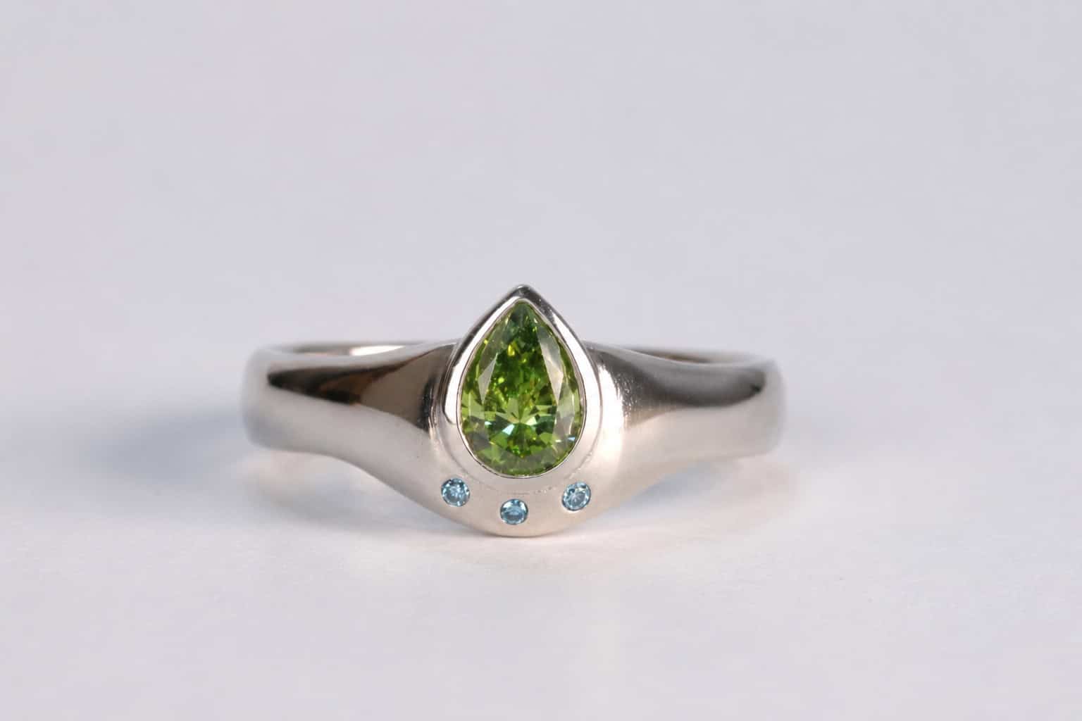 Platina verlovingsring met groene en blauwe diamanten, op maat vervaardigd in het atelier van Burgant.